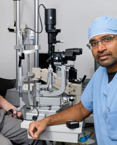 Ophthalmologist Raj Maturi, MD, with a patient in his clinic.