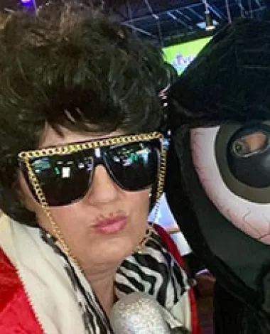 A person dressed in a Halloween costume poses next to an inflatable eyeball