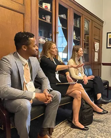A group of AAO members sit in an office talking during the Mid-Year Forum