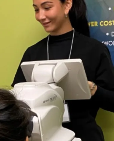 A doctor stands in front of a retinopathy screening machine