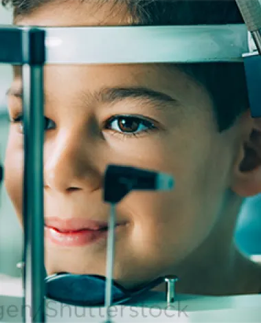A smiling child sits during an eye exam