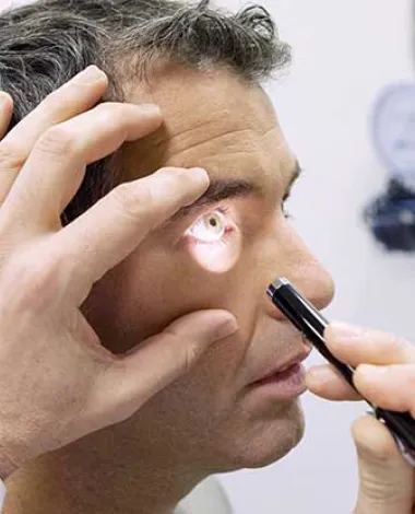 A doctor shines a light into a patient's eyes during an eye exam