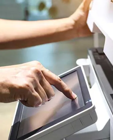 A person tapping the controls of a large photocopy and fax machine