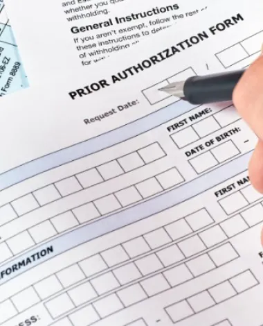 A closeup of someone filling out a prior authorization form