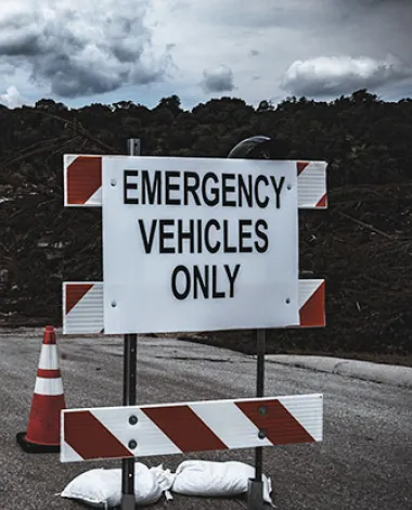A damaged road with a roadblock sign that reads "emergency vehicles only"