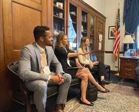 A group of AAO members sit in an office talking during the Mid-Year Forum
