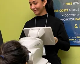 A doctor stands in front of a retinopathy screening machine