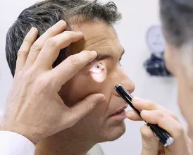 A doctor shines a light into a patient's eyes during an eye exam