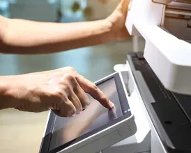 A person tapping the controls of a large photocopy and fax machine