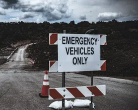A damaged road with a roadblock sign that reads "emergency vehicles only"